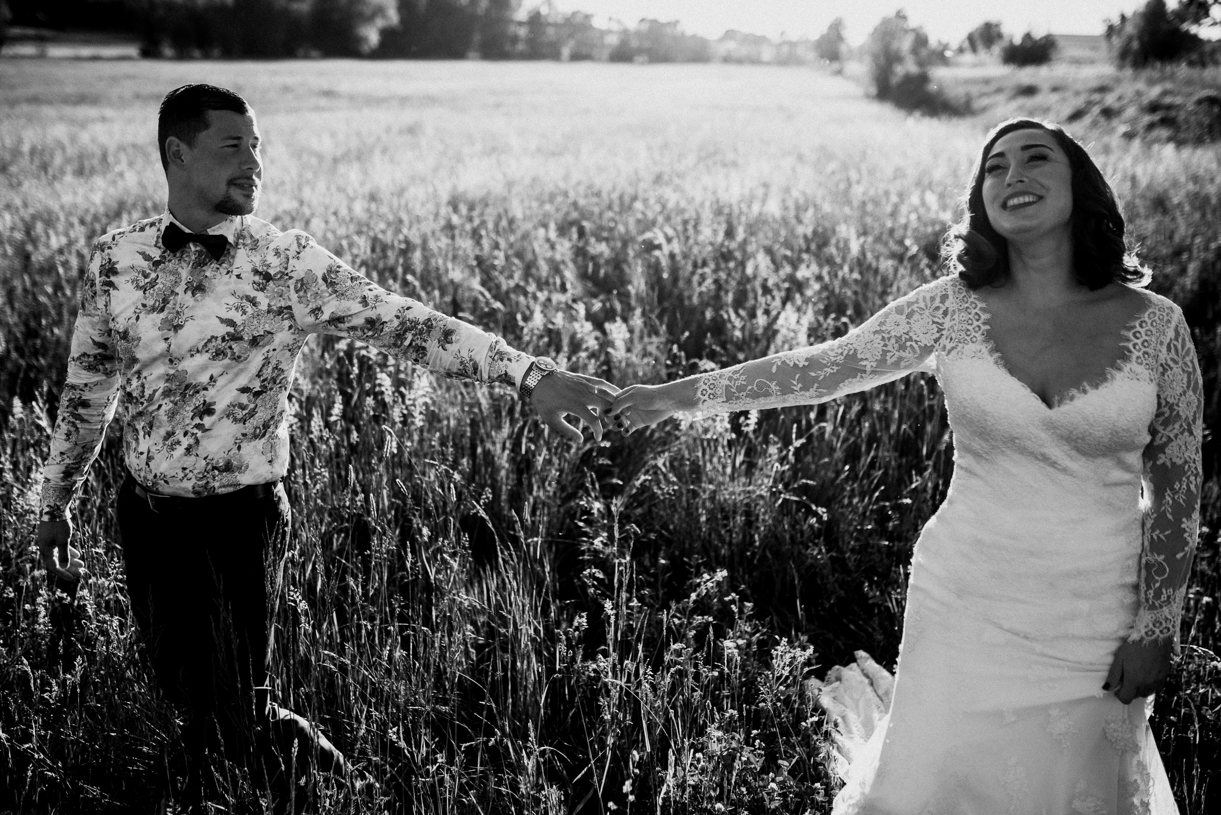 Deutsch-türkische Hochzeit: Brautpaar steht Hand in Hand vor einem Kornfeld