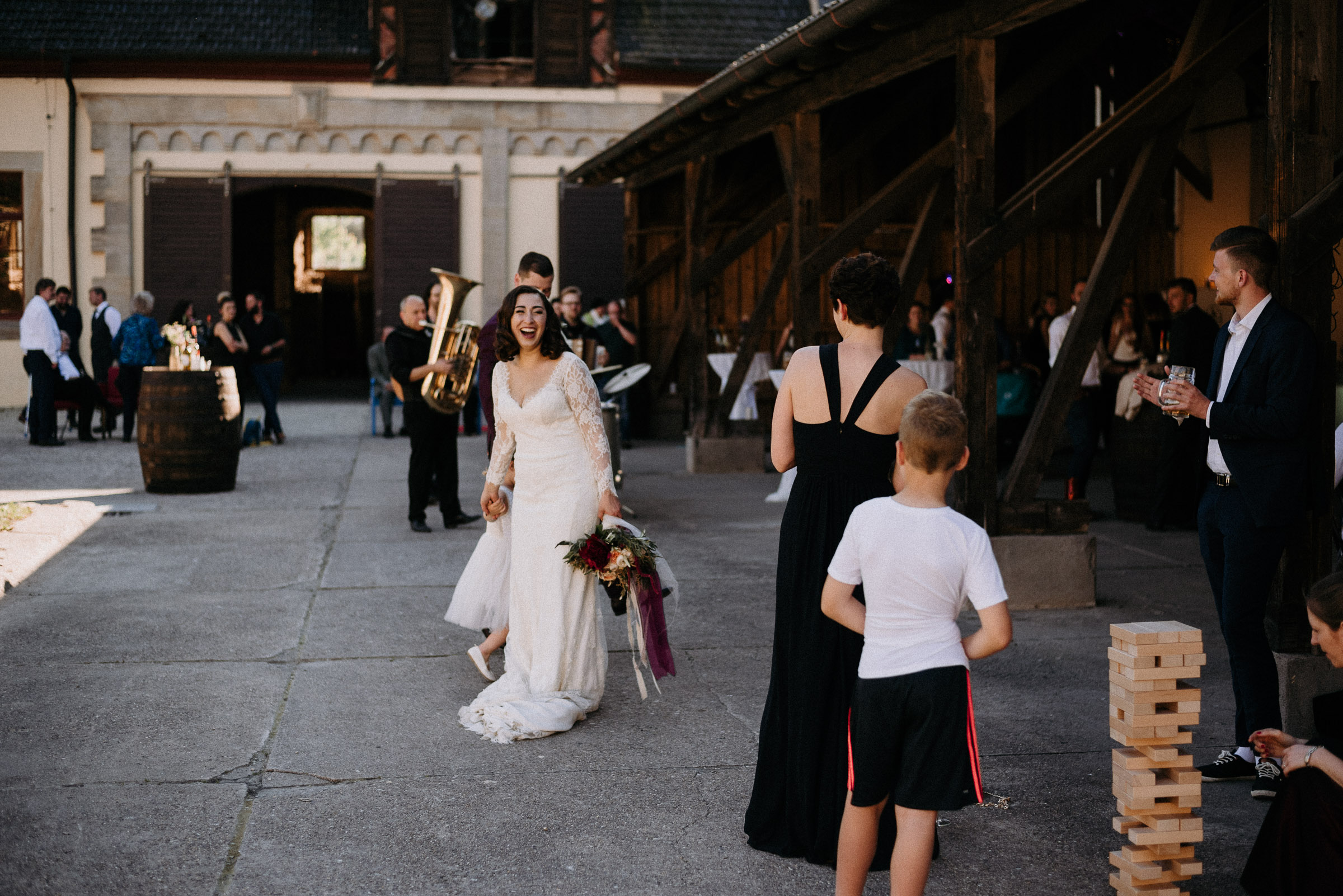 Deutsch-türkische Hochzeit: lachende Braut mit Blumenmädchen und Hochzeitsgästen im Schlosshof