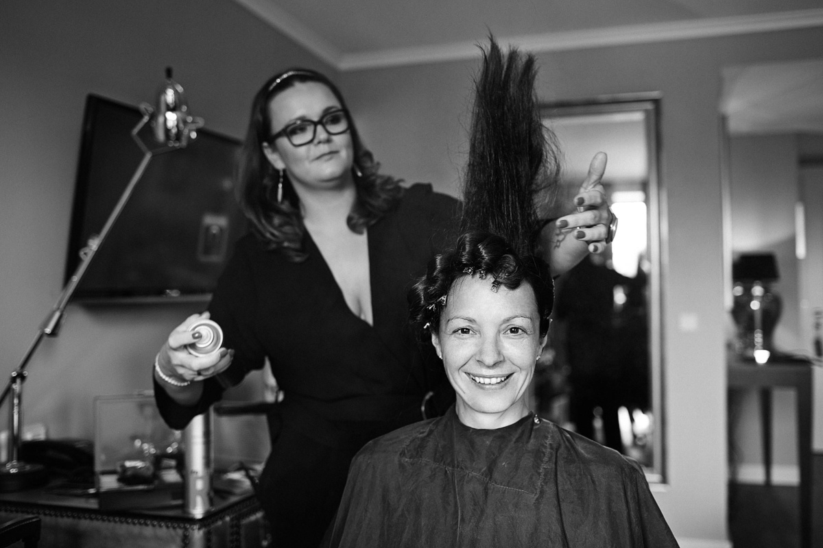 Hochzeit in einem Wellnesshotel: der Braut stehen vom Haarspray die Haare gerade nach oben, sie lacht