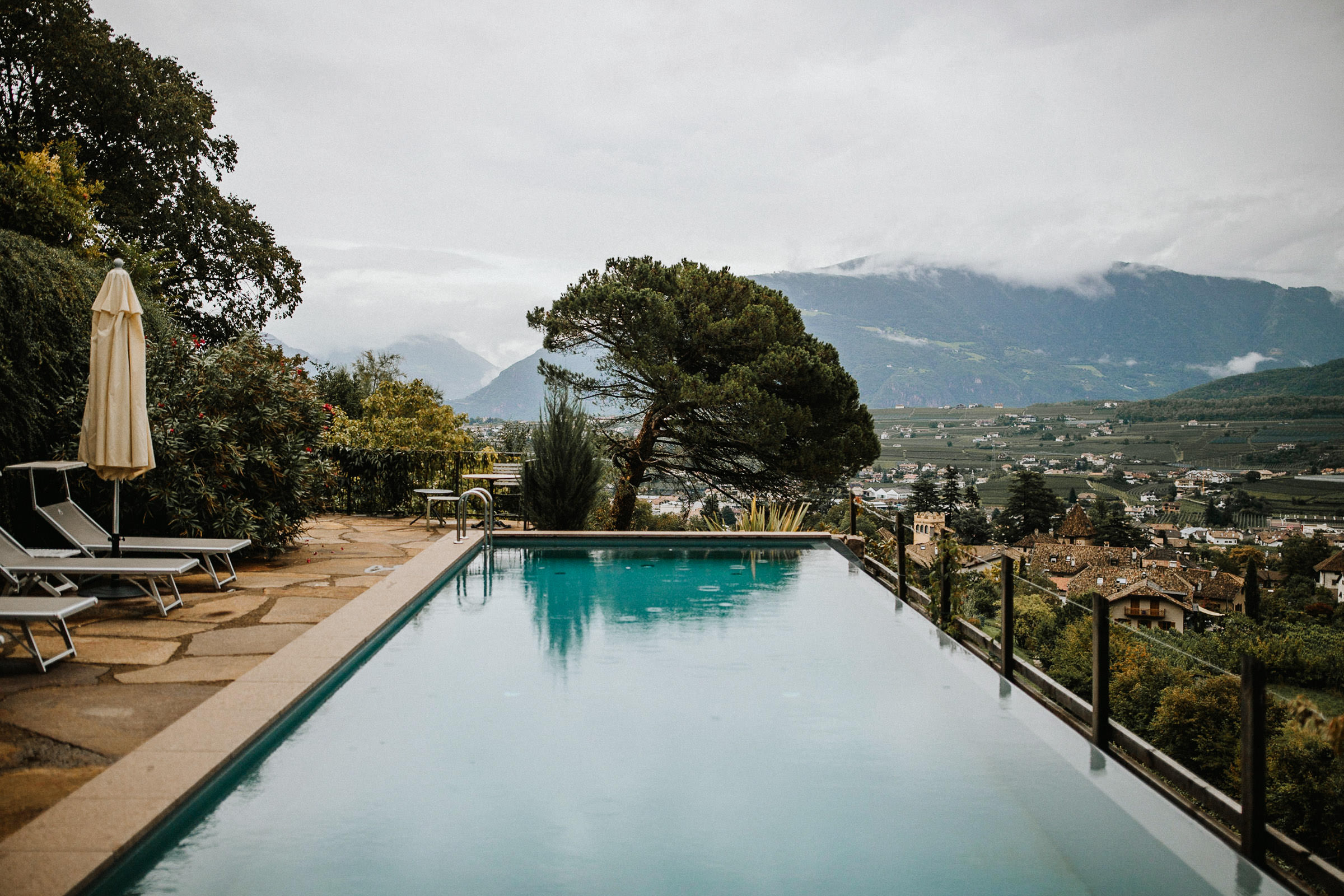 Schlosshochzeit: Regentropfen auf der Oberfläche des Swimmingpools, im Hintergrund das Bergpanorama