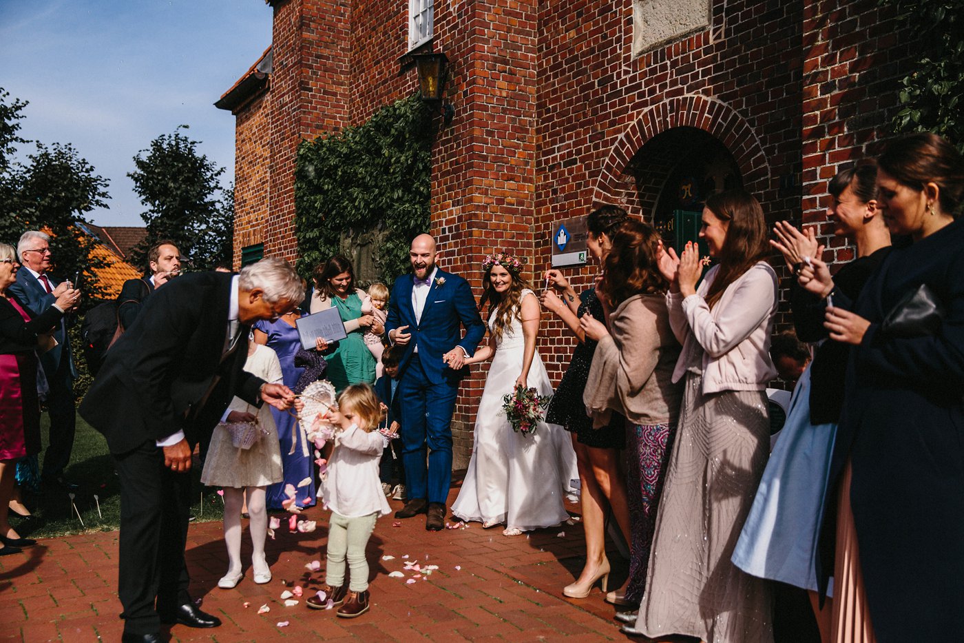 Urbane Hochzeit: das Brautpaar kommt freudestrahlend aus der Kirche, die Gäste jubeln