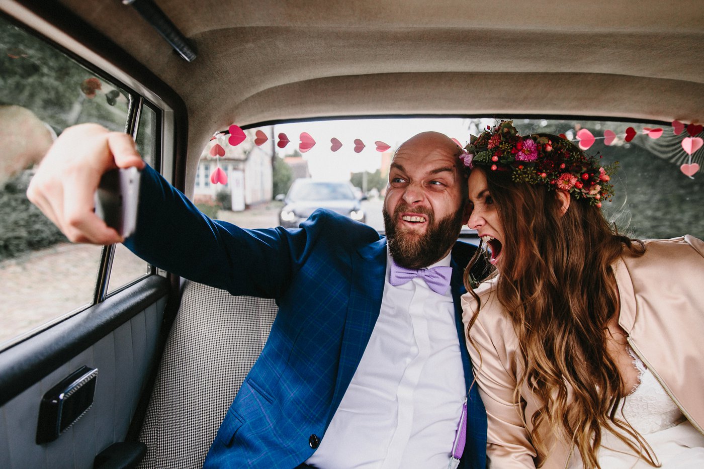 Urbane Hochzeit: Brautpaar macht Selfie im Hochzeitsauto