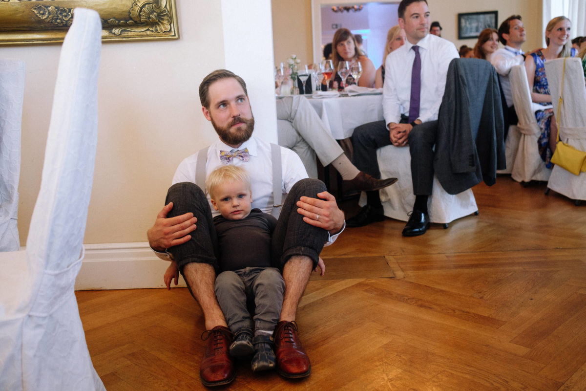 Vintage-Hochzeit: Hochzeitsgast hockt mit einem Kind am Boden